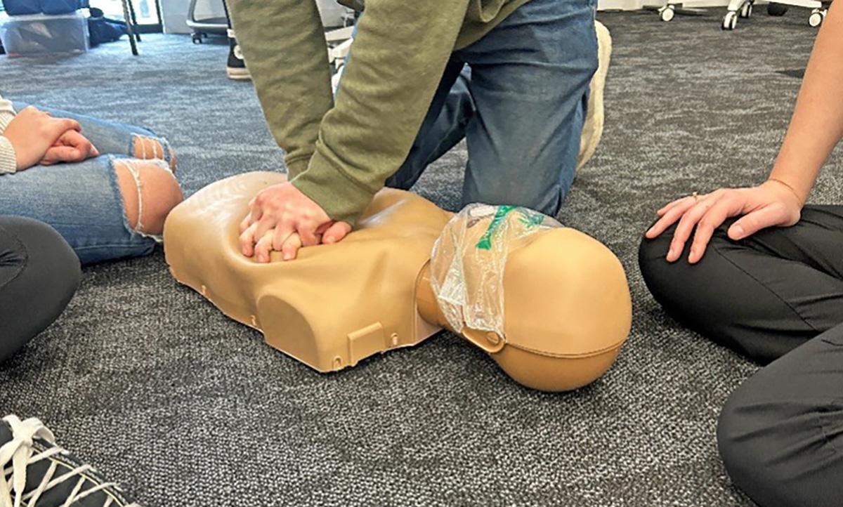 Students performing compressions on cpr model.